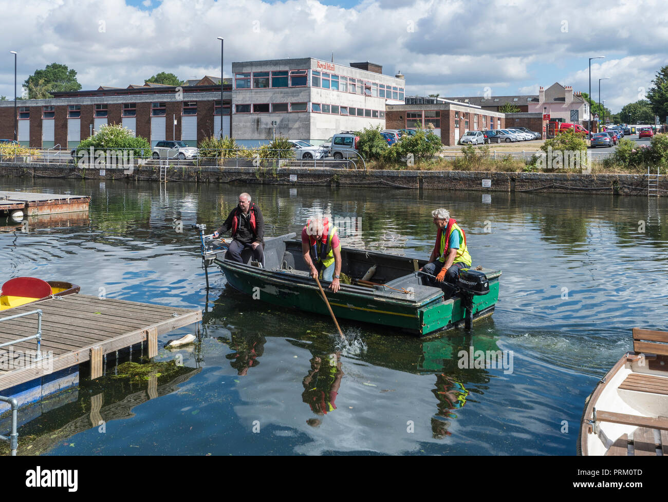 Elderley Mann in einem Boot Kommissionierung Wurf zu sauberem Wasser in Chichester Kanal in Chichester, West Sussex, England, UK. Stockfoto