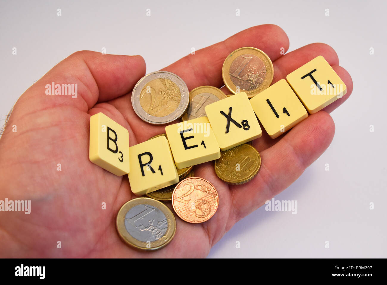 Hand mit Euro-bargeld und Brexit Schriftzug in Scrabble Fliesen auf weißem Hintergrund. Europäische Union Volksabstimmung zu verlassen, Politik Stockfoto