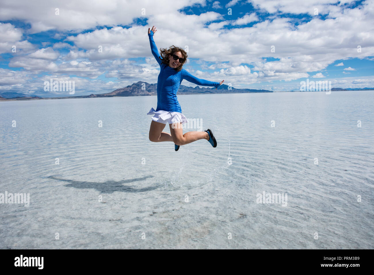 Eine Frau springt auf den Bonneville Salt Flats, wenn die Salinen sind im Frühjahr überflutet. Stockfoto