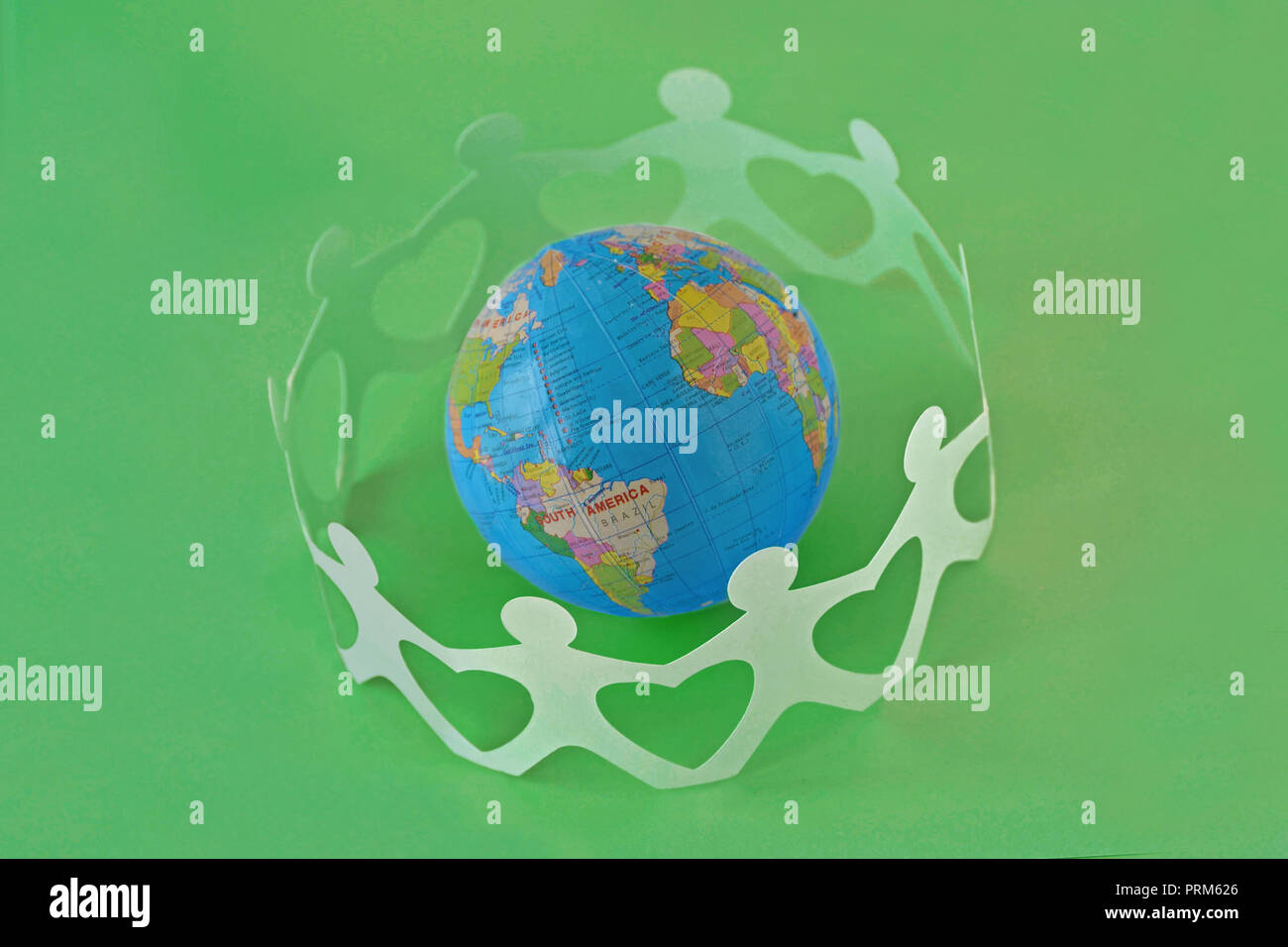 Papier Menschen in einem Kreis um die Erdkugel auf grünem Hintergrund - Begriff der Liebe und Ökologie Stockfoto