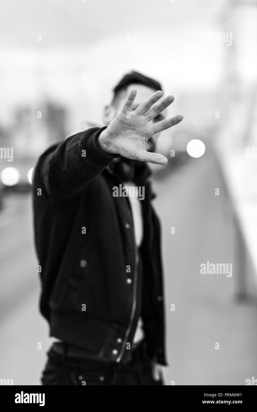 Ein junger Hippie Mann bedeckte sein Gesicht mit der Hand in einem städtischen Umfeld. Stockfoto