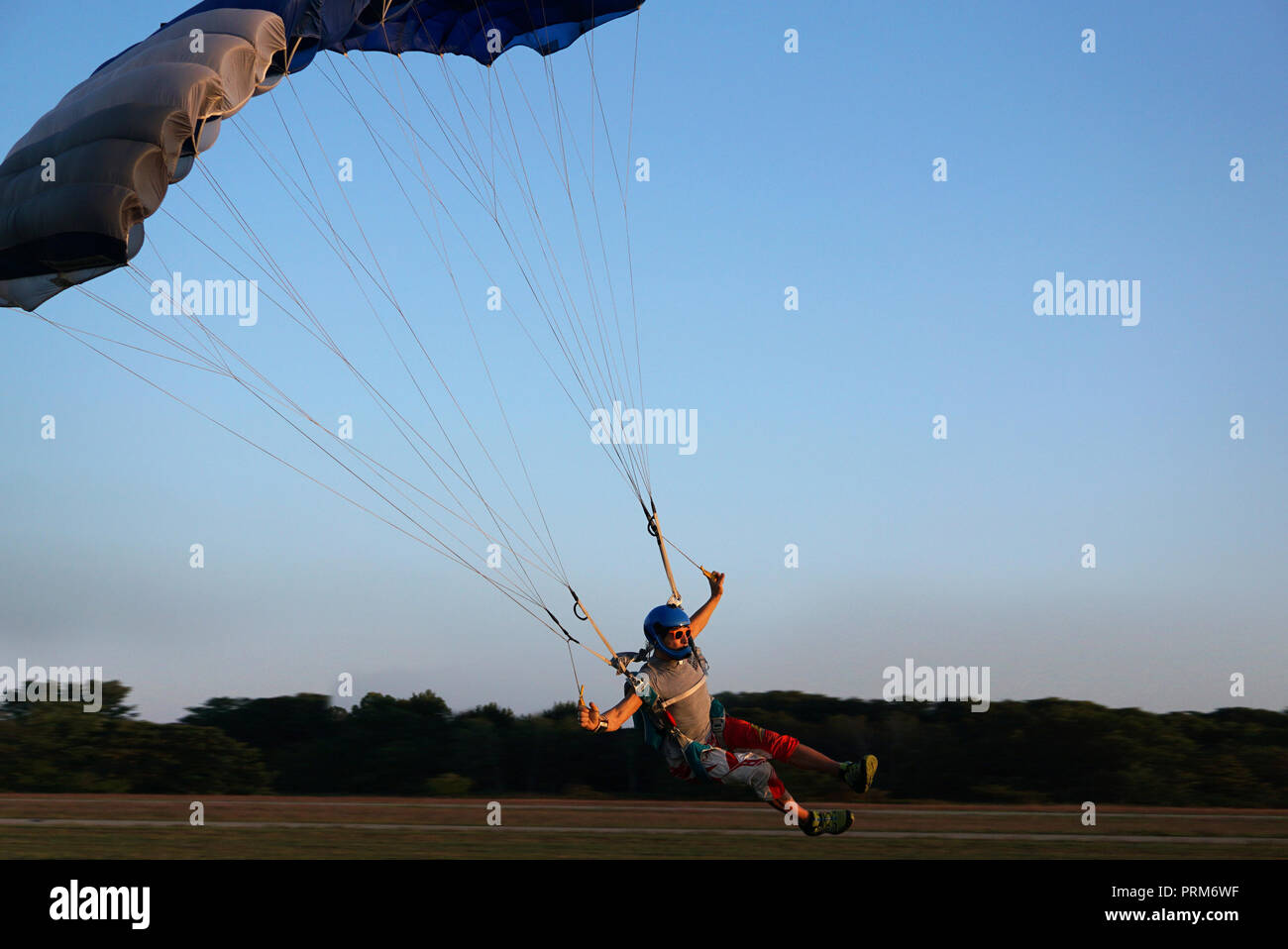 Skydiver unter einem dunkelblauen wenig Überdachung eines Fallschirm ist Landung auf dem Flugplatz, close-up. High-speed Landung der Fallschirmspringer vor dem Hintergrund der Stockfoto