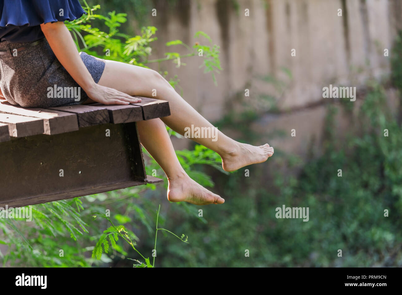 Die Beine der Frau hängt über einem Holzsteg Stockfoto