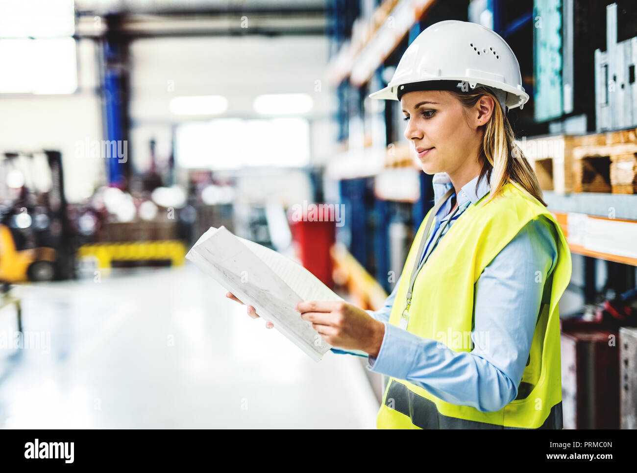 Ein Porträt einer Frau Ingenieur in einer Fabrik holding Schreibarbeit. Stockfoto