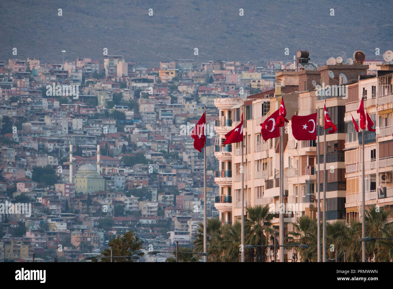 Türkische Flaggen fliegen vor den Apartmentgebäuden am Wasser in Izmir, Türkei Stockfoto