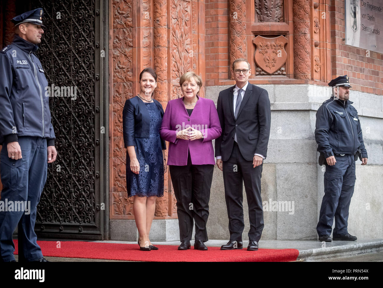 03 Oktober 2018, Berlin: Bundeskanzlerin Angela Merkel (CDU, M) bildet ein Diamant mit den Händen, während Sie neben Michael Müller (SPD), Regierender Bürgermeister von Berlin und Präsident des Bundesrates, und seine Frau Claudia Müller vor dem Roten Rathaus anlässlich der Feierlichkeiten zum Tag der Deutschen Einheit. Foto: Michael Kappeler/dpa Stockfoto