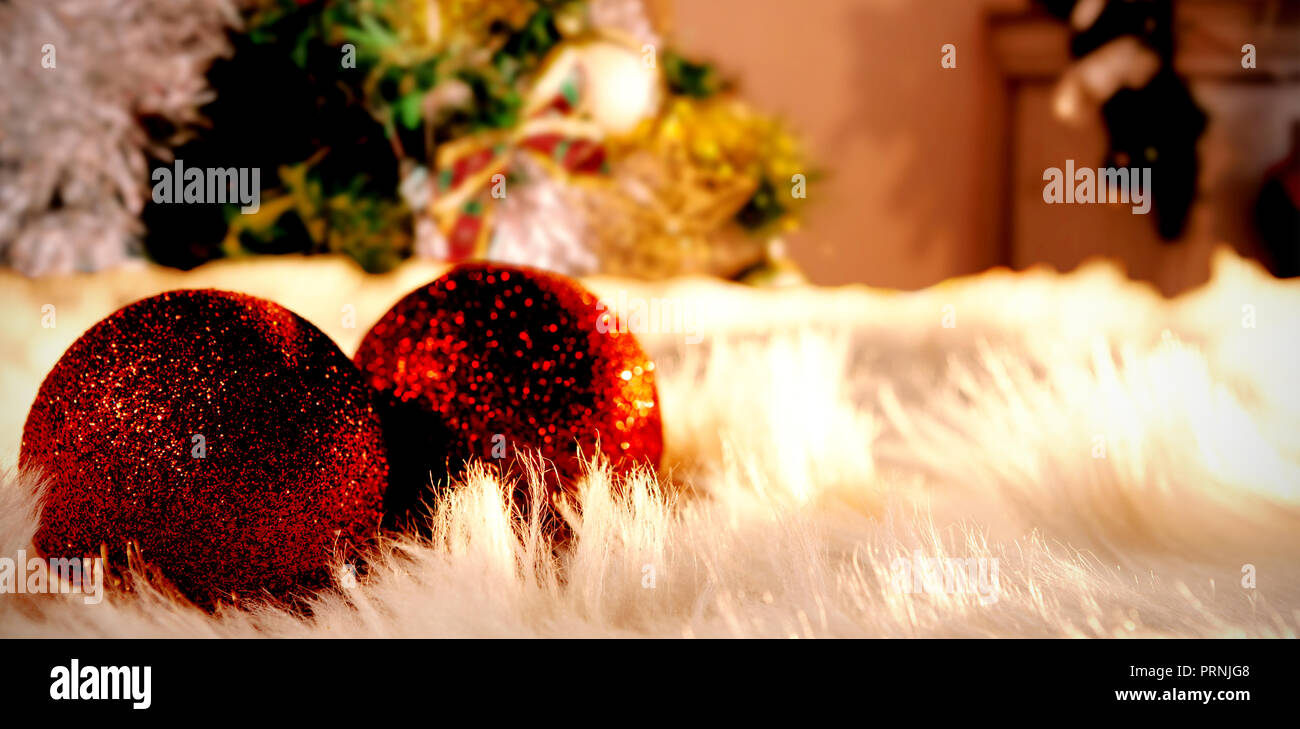 Das zusammengesetzte Bild von zwei roten Weihnachtskugeln auf weißem Fell Stockfoto
