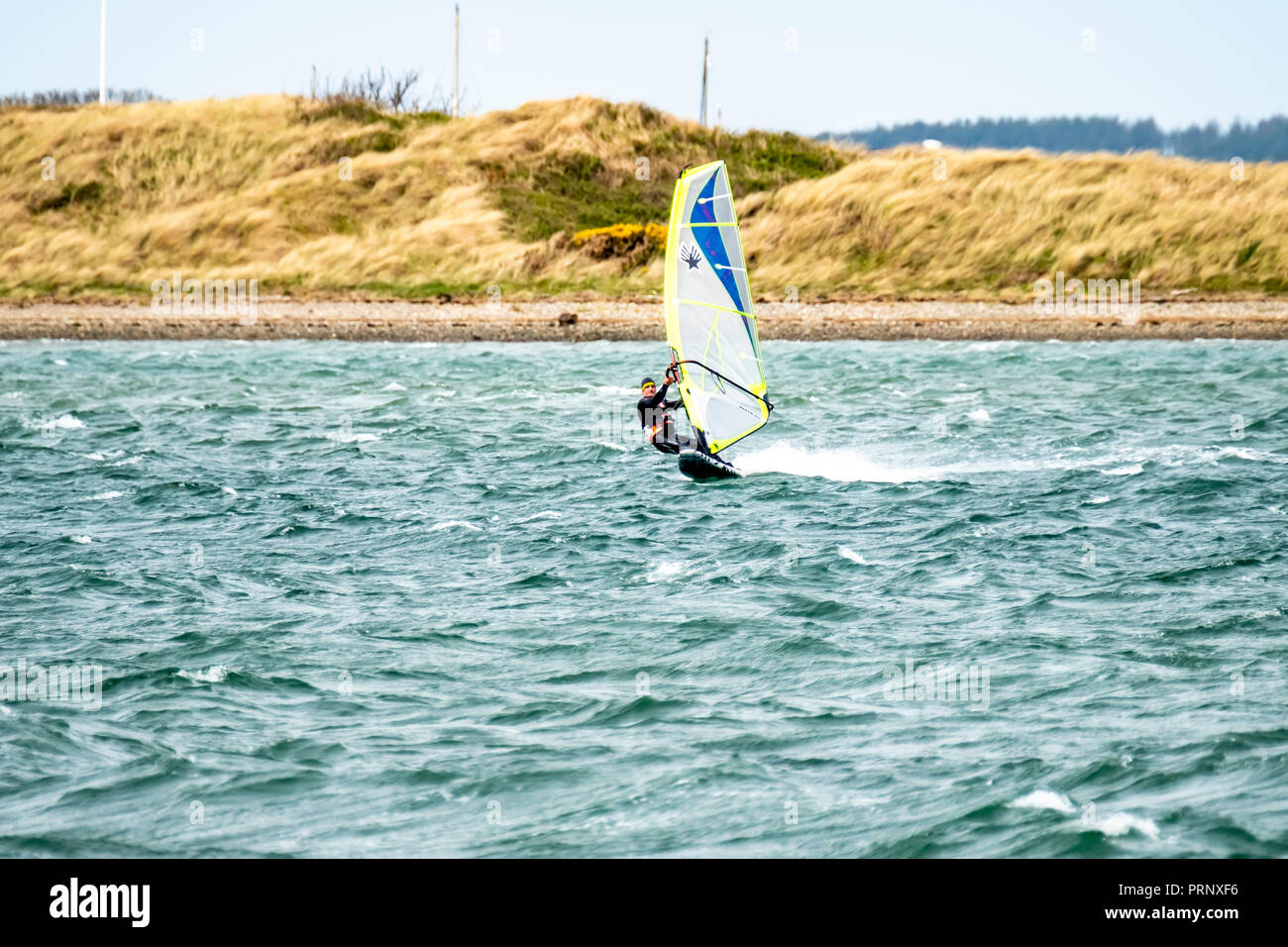 CAERNARFON/Wales - 01 Mai 2018: Mann Windsurfen in der Nähe der Stadt. Stockfoto