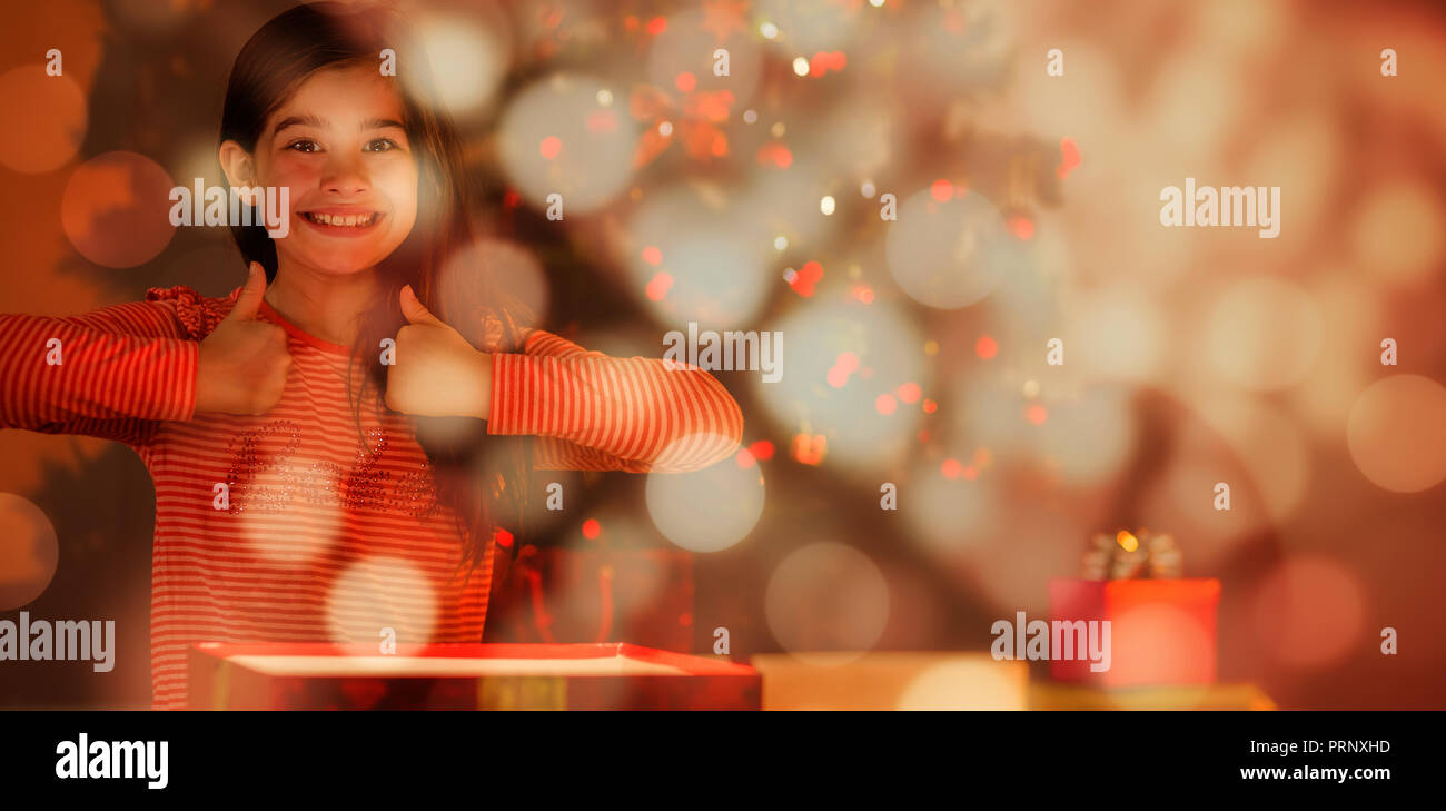 Zusammengesetztes Bild von kleinen Mädchen eine leuchtende Weihnachtsgeschenk öffnen Stockfoto