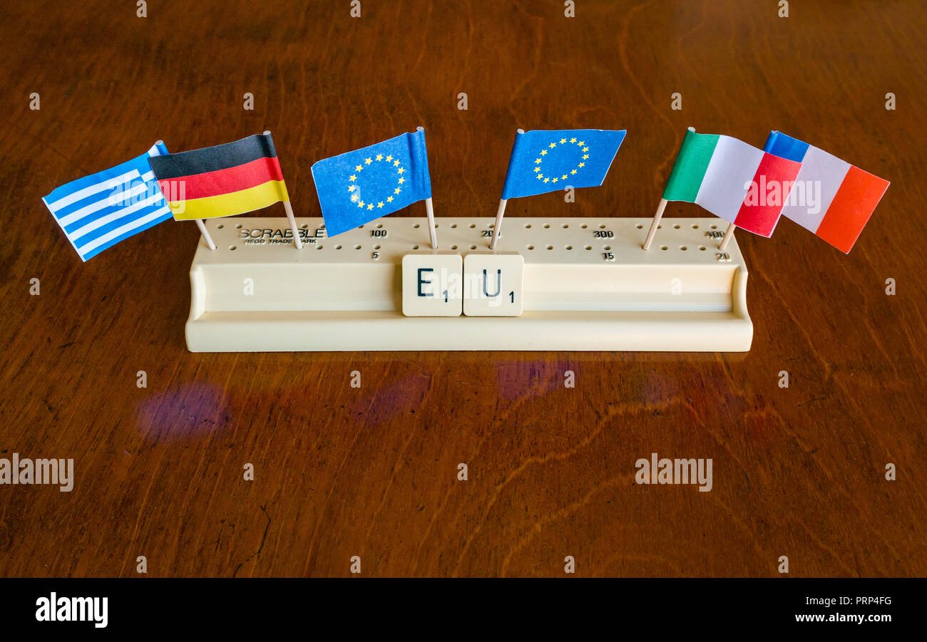 Scrabble Buchstaben Rechtschreibung EU in Scrabble Fach, das mit der Europäischen Union, der deutschen, der griechischen Französische und italienische Flaggen auf Mahagoni Hintergrund Stockfoto