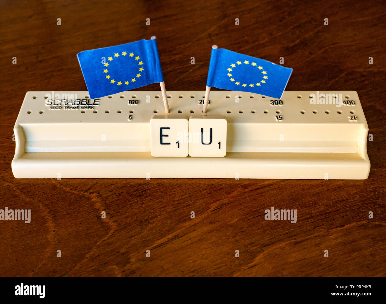 Scrabble Buchstaben Rechtschreibung EU in Scrabble Fach mit Europäische Union Flaggen auf dunklem Mahagoni Hintergrund Stockfoto