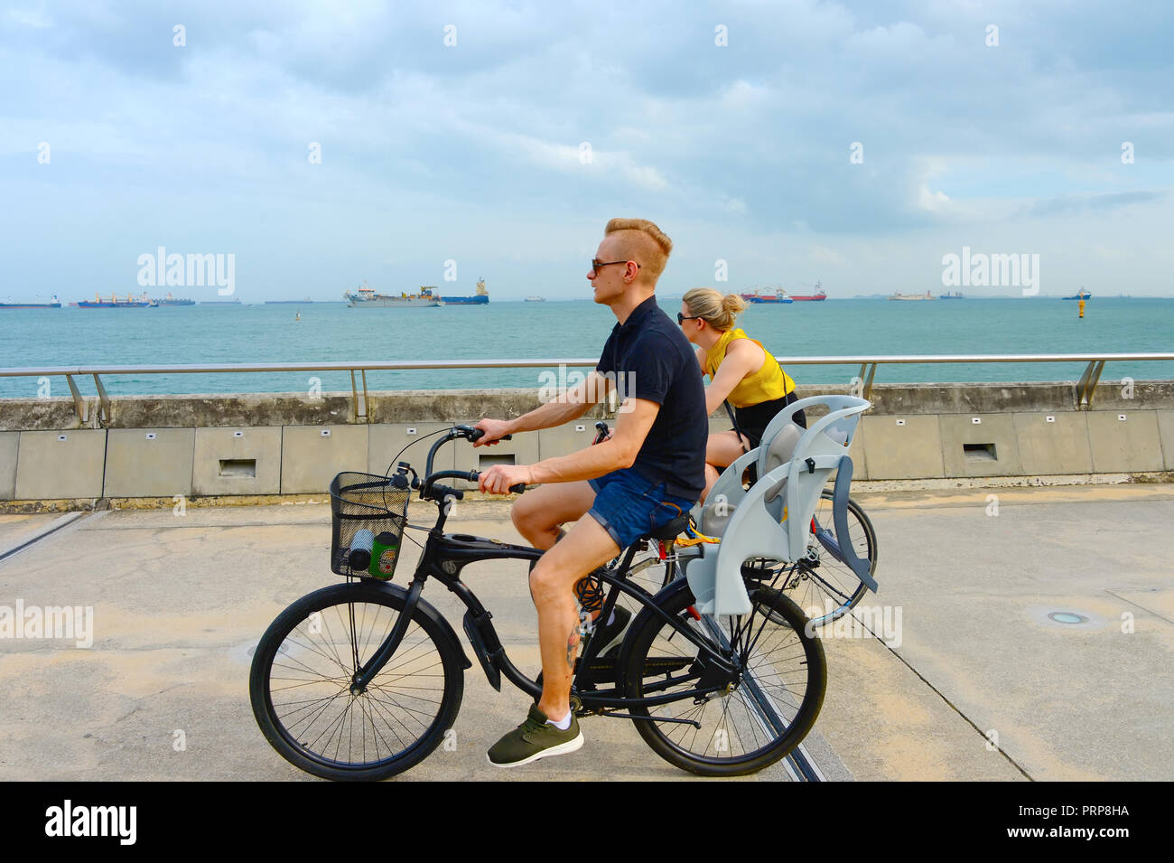 Singapur - Februar 6, 2017: Paar Reiten Fahrräder am Hafen von Singapur. Singapur ist wichtiges Finanzzentrum in Asien Stockfoto