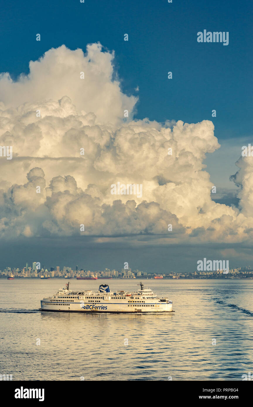 BC Ferries Fähre Königin der Cowichan Segel außerhalb der English Bay, in warmen Nachmittag Licht, Straße von Georgia, British Columbia, Kanada. Downtown Vancouver mit einem großen Cumulus cloud Overhead im Hintergrund. Stockfoto