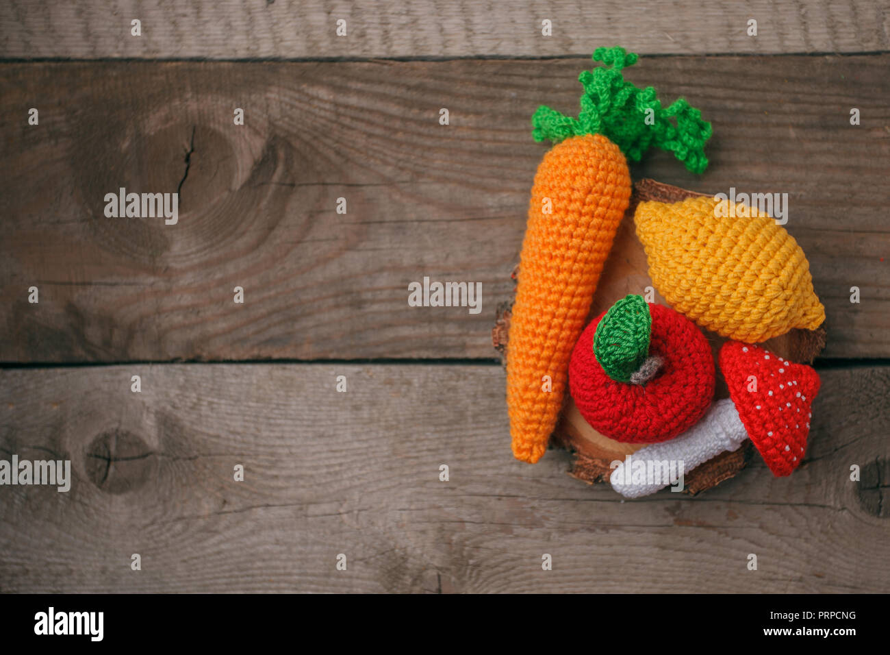 Set aus Gewirken Spielzeug Zitrone, Karotte, Apfel, amanita auf Holz- Hintergrund. Früher taktile Entwicklung der Kinder, Handwerk Spielzeug, vegetarisches Menü Konzept, Stockfoto