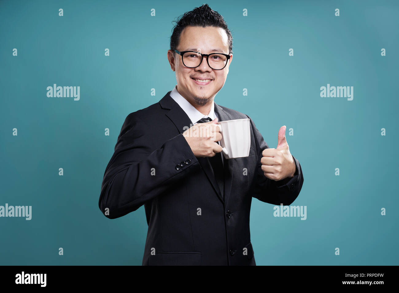 Geschäftsmann in Anzug lächeln und genießen Sie Kaffee mit Daumen oben-Geste. Stockfoto