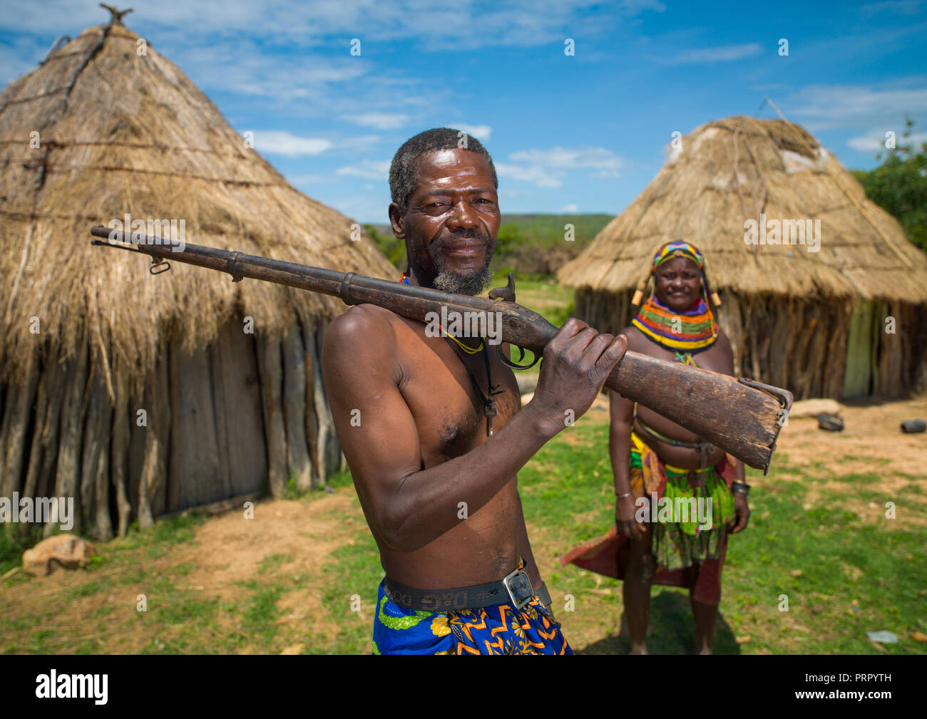 Mumuhuila Stamm Mann mit einem Gewehr in seinem Dorf, Huila Provinz, Chibia, Angola Stockfoto