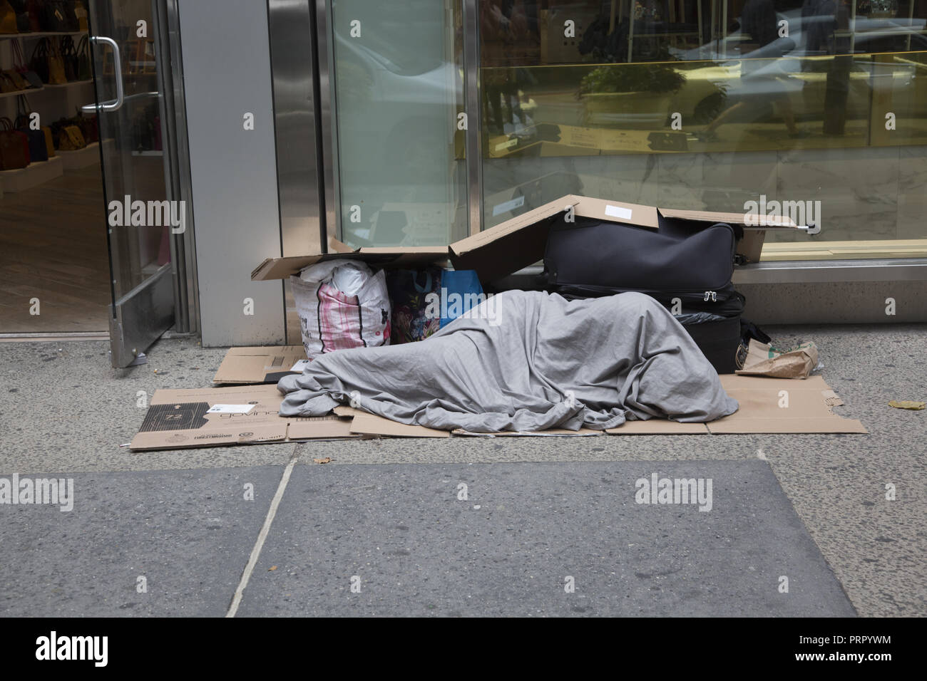 Schlafenden obdachlosen Mann auf einem Bürgersteig in Midtown Manhattan als pedestr 4 ians Spaziergang durch. Stockfoto