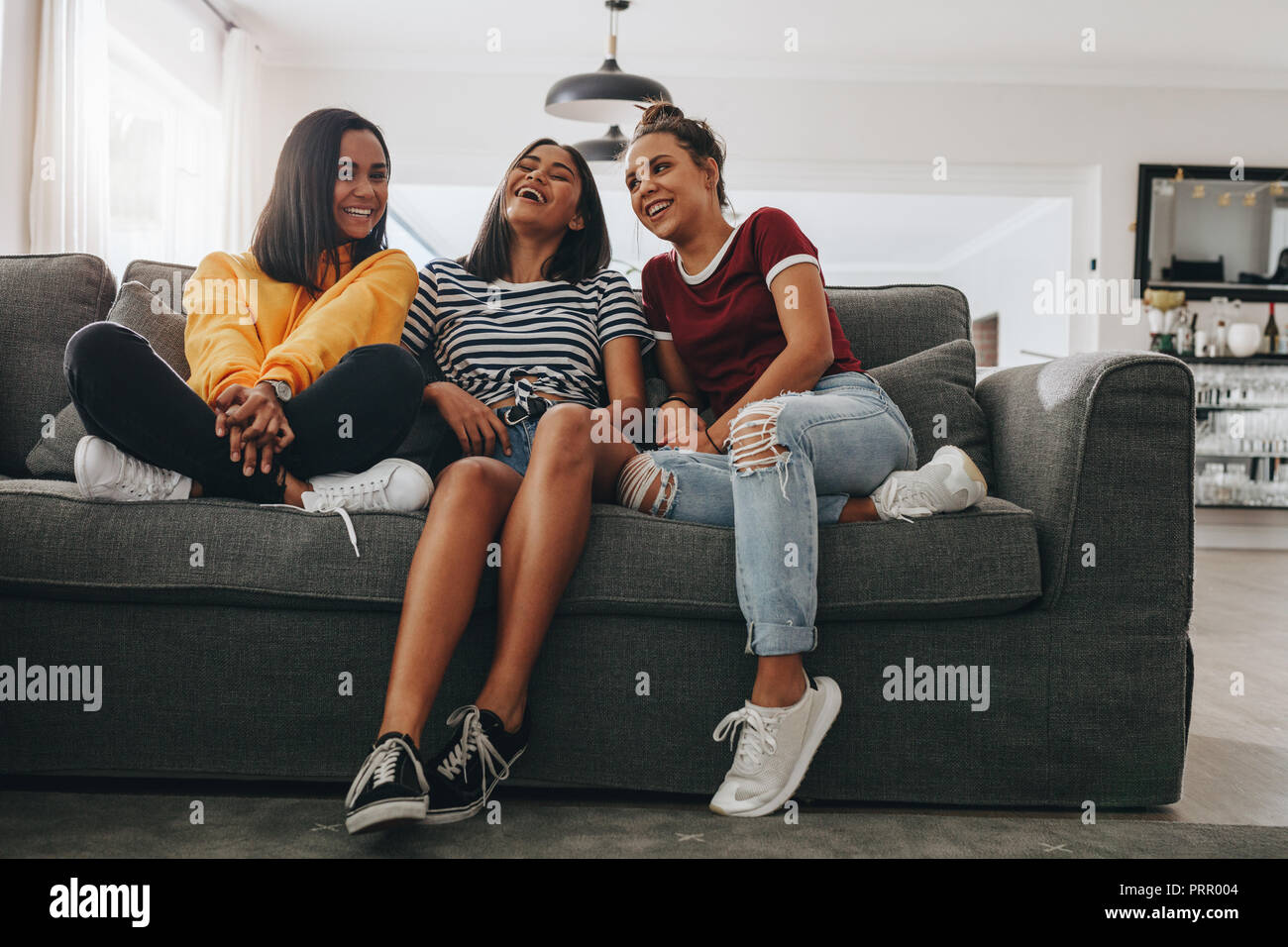 Drei junge Mädchen sitzen zusammen auf der Couch im Wohnzimmer und Lachen. Junge Mädchen haben Spaß zusammen sitzt und spricht bei einem sleepover. Stockfoto