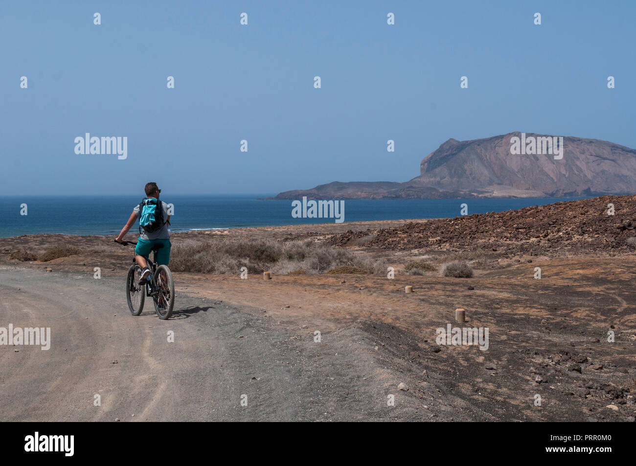 Lanzarote, Kanarische Inseln: junge Radfahren auf dem Schmutz der Straße zum Strand Playa de Las Conchas im Norden von La Graciosa, die Inselgruppe Chinijo Inseln Stockfoto