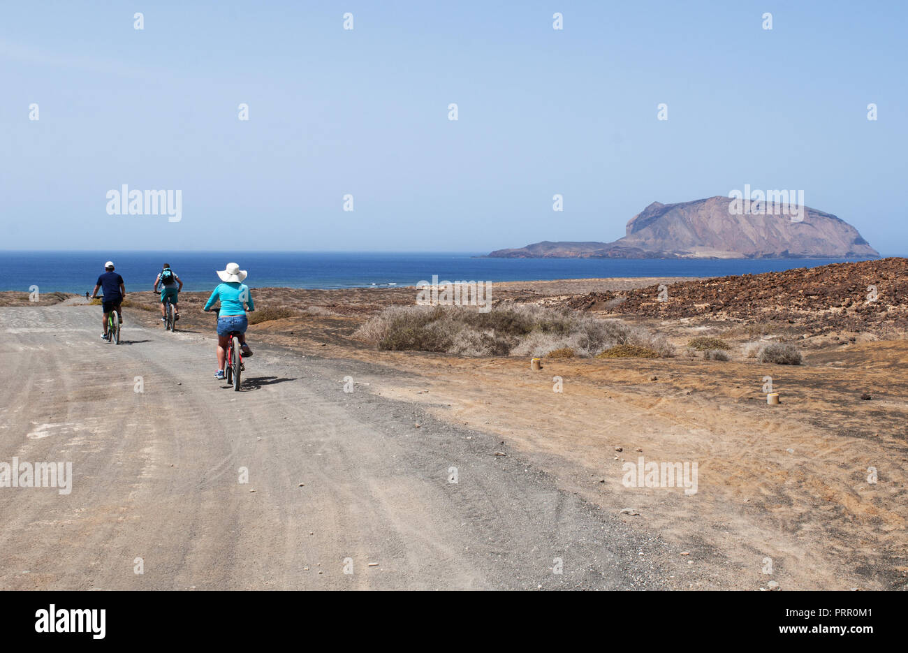 Lanzarote, Spanien: Menschen Biken auf der unbefestigten Straße vom Strand Playa de Las Conchas im Norden von La Graciosa, die Inselgruppe Chinijo Inseln Stockfoto