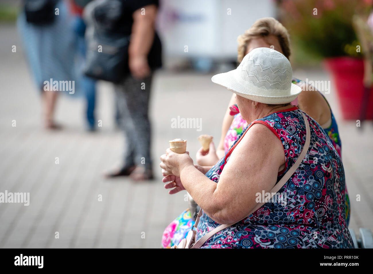 RIGA, Lettland - 18. AUGUST 2018: Zwei alte Frauen auf einer Bank sitzen und ein Eis essen. Stockfoto