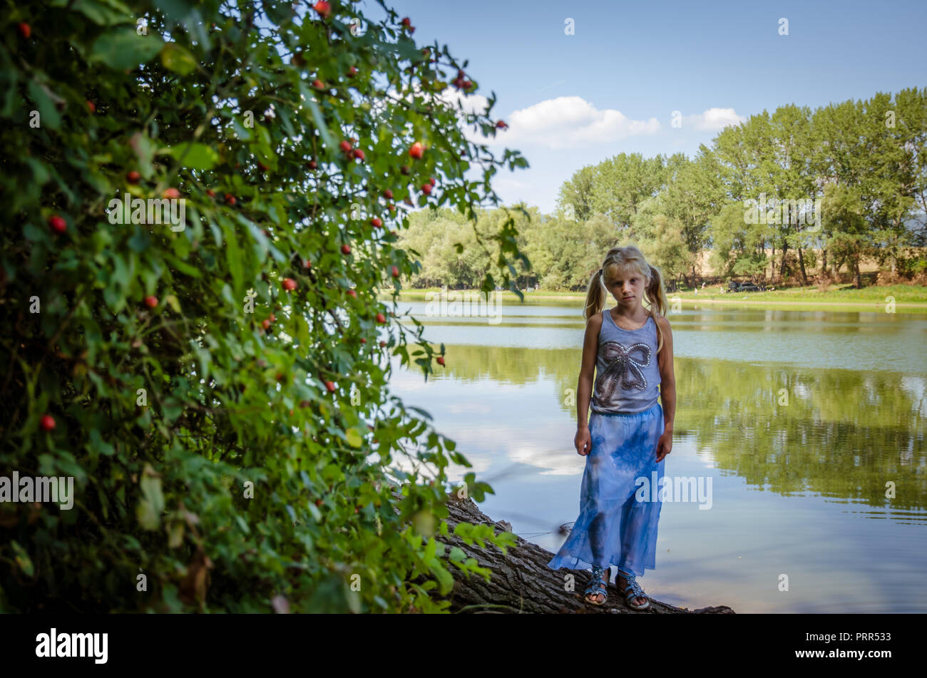 Kleines Mädchen gehen unter Zweigen vom Ufer Stockfoto