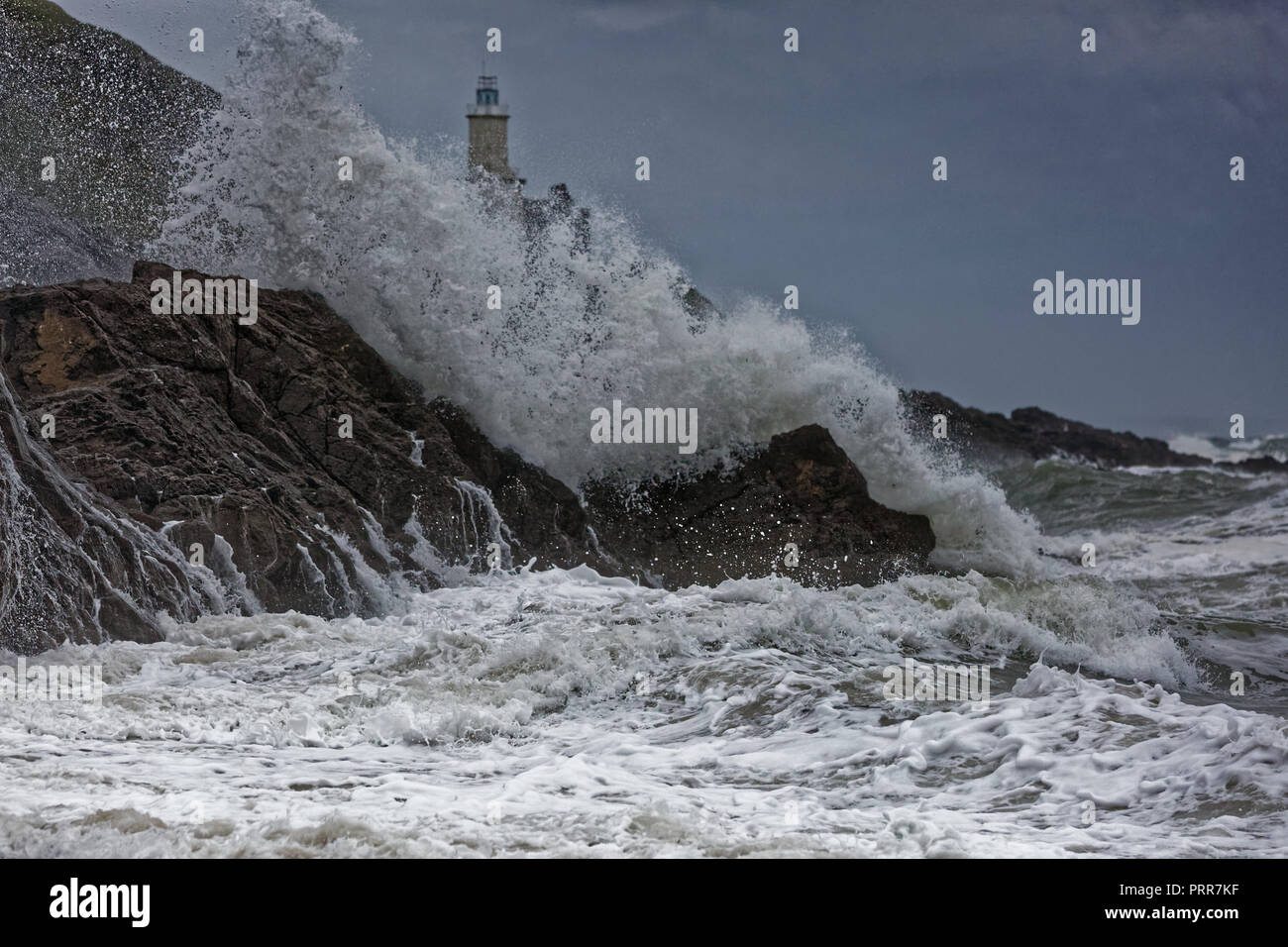 Wellen gegen die Felsen durch Mumbles Leuchtturm in Armband Bay, Swansea, Wales, Großbritannien Stockfoto