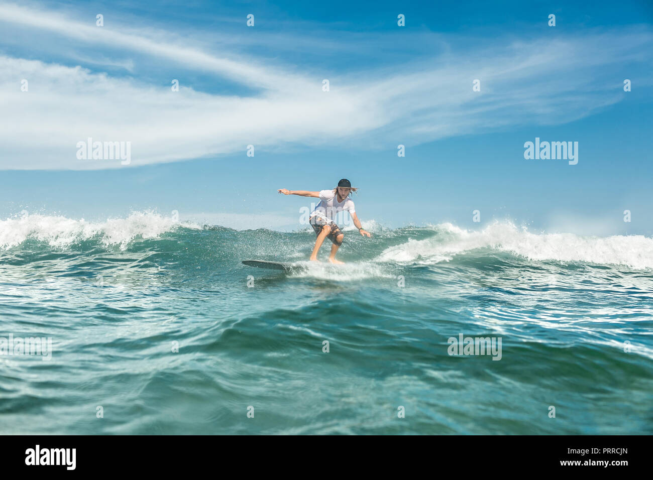 Junge männliche Surfer Reiten in Ocean in Nusa Dua, Bali, Indonesien Stockfoto