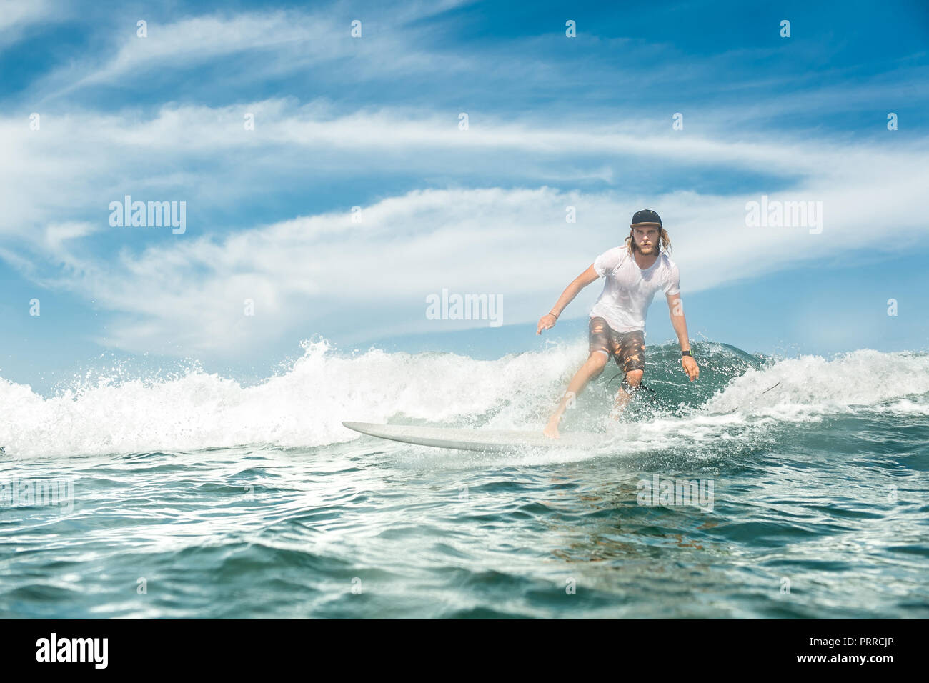 Stattliche männliche Sportler Surfen auf den Wellen im Ozean am Sandstrand von Nusa Dua, Bali, Indonesien Stockfoto