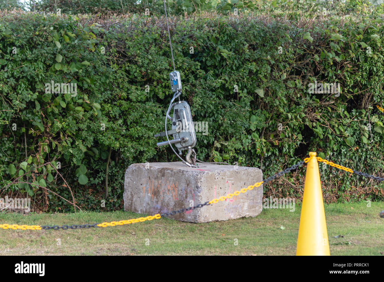 Betonklotz als Ankerpunkt für eine Stahl Kerl Kabel von einer mobilen Plattform auf einem Strom pylon behinf Kunststoff Barriere Kette Stockfoto