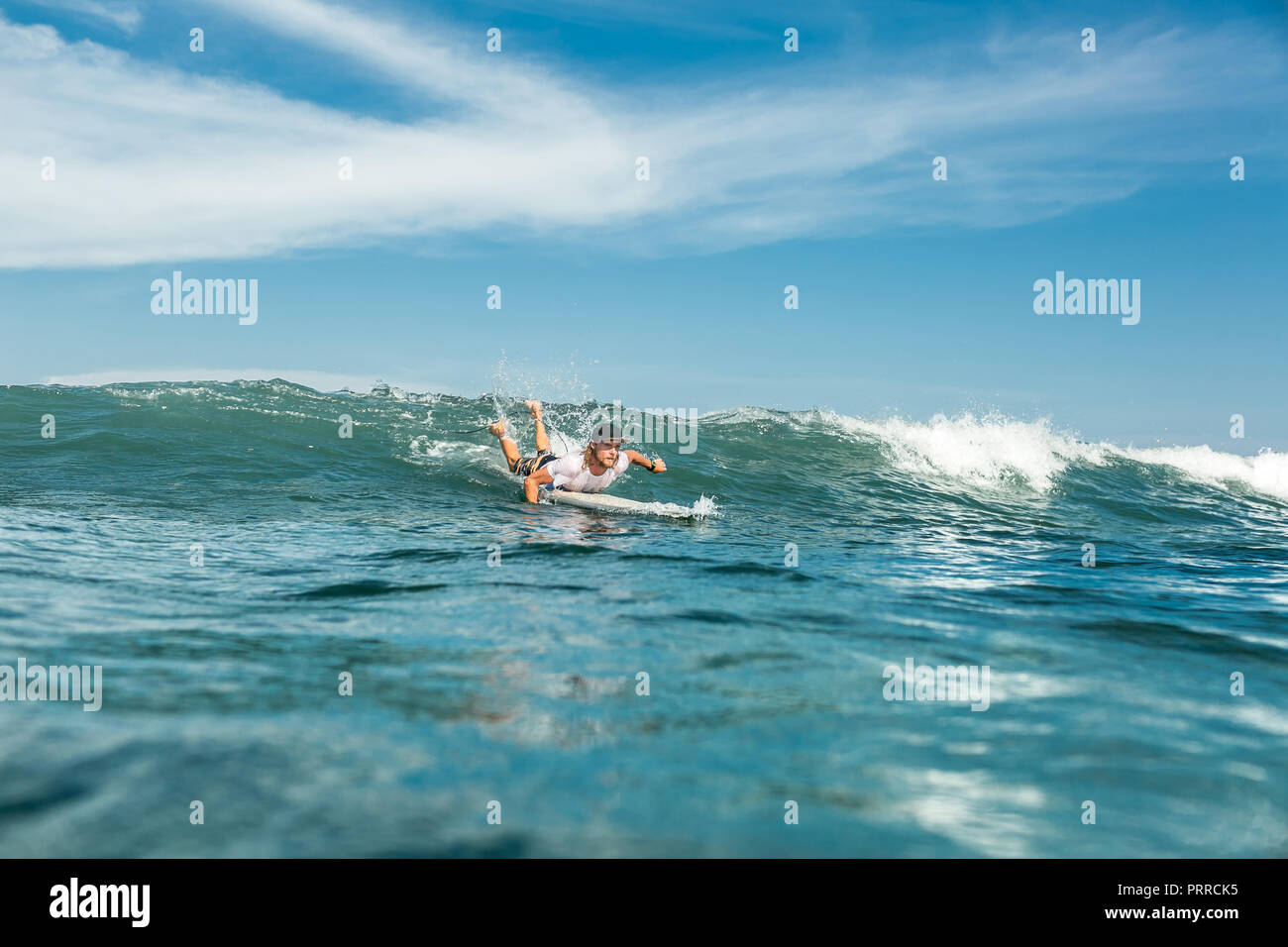 Fernsicht auf männliche Sportler schwimmen auf Surfen im Meer am Sandstrand von Nusa Dua, Bali, Indonesien Stockfoto