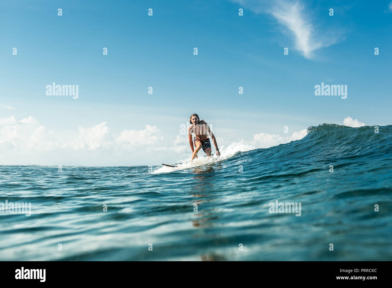 Fernsicht auf stattliche männliche Surfer reiten Wellen im Ozean am Sandstrand von Nusa Dua, Bali, Indonesien Stockfoto