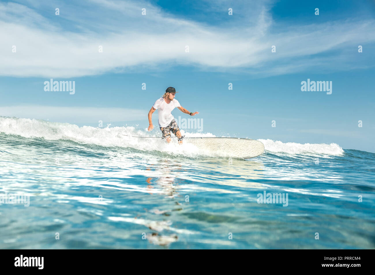 Fernsicht auf männliche Surfer Reiten an Bord im Ozean am Sandstrand von Nusa Dua, Bali, Indonesien Stockfoto