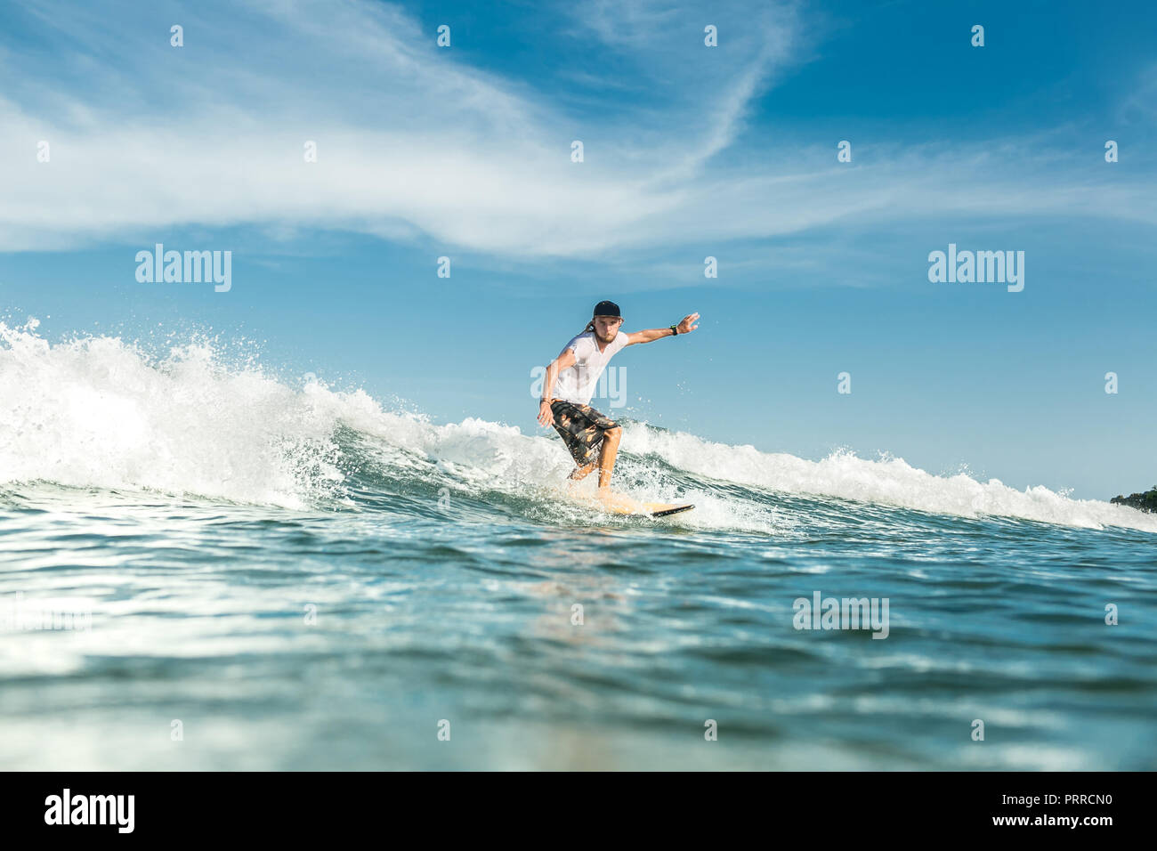 Junge männliche Surfer reiten Wellen im Ozean am Sandstrand von Nusa Dua, Bali, Indonesien Stockfoto