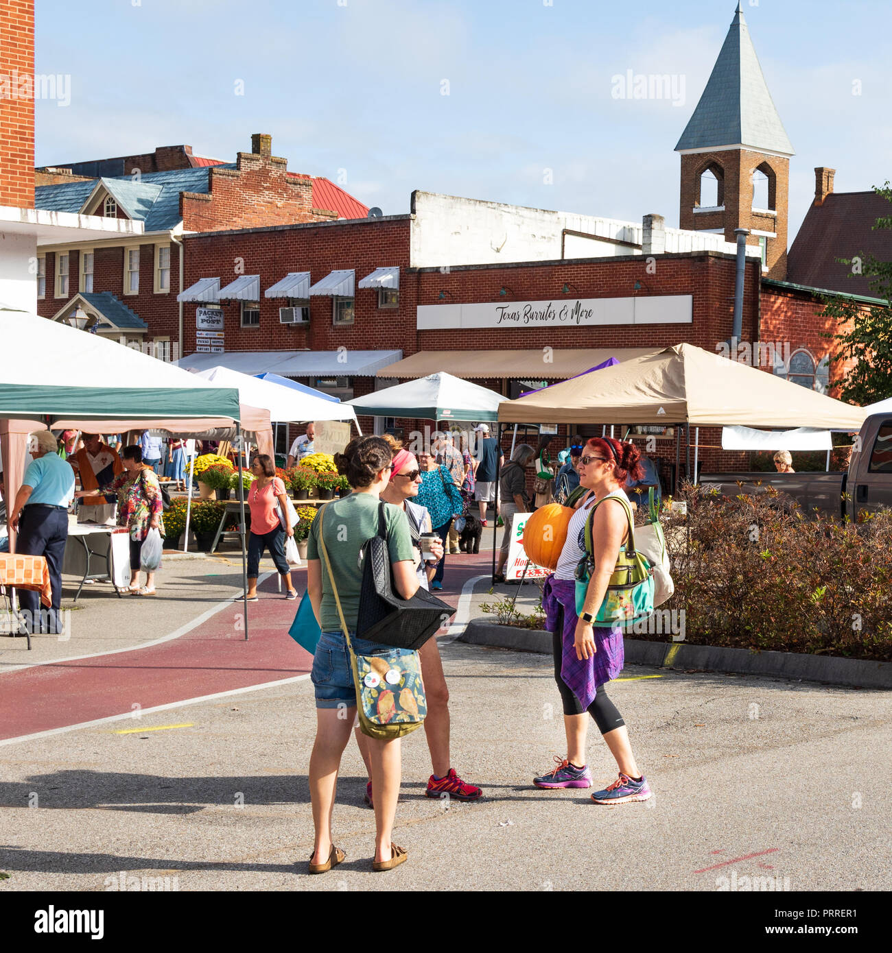 Erwin, TN, USA -9/29/18: Während 3 Frauen sprechen, und hält man große Kürbis bei Farmers' Market. Stockfoto
