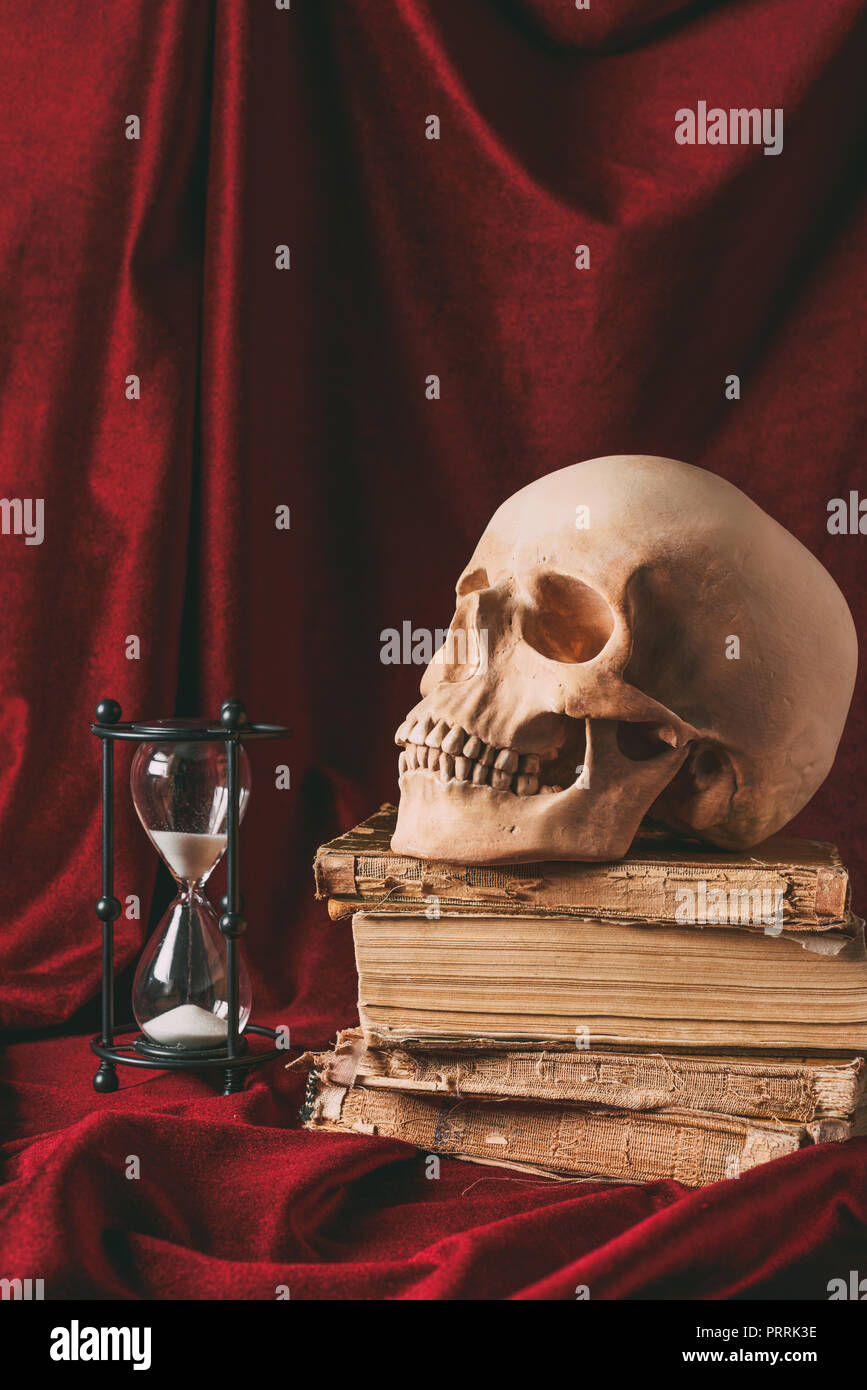 Halloween Totenkopf auf alten Bücher mit der Sanduhr am roten Tuch Stockfoto