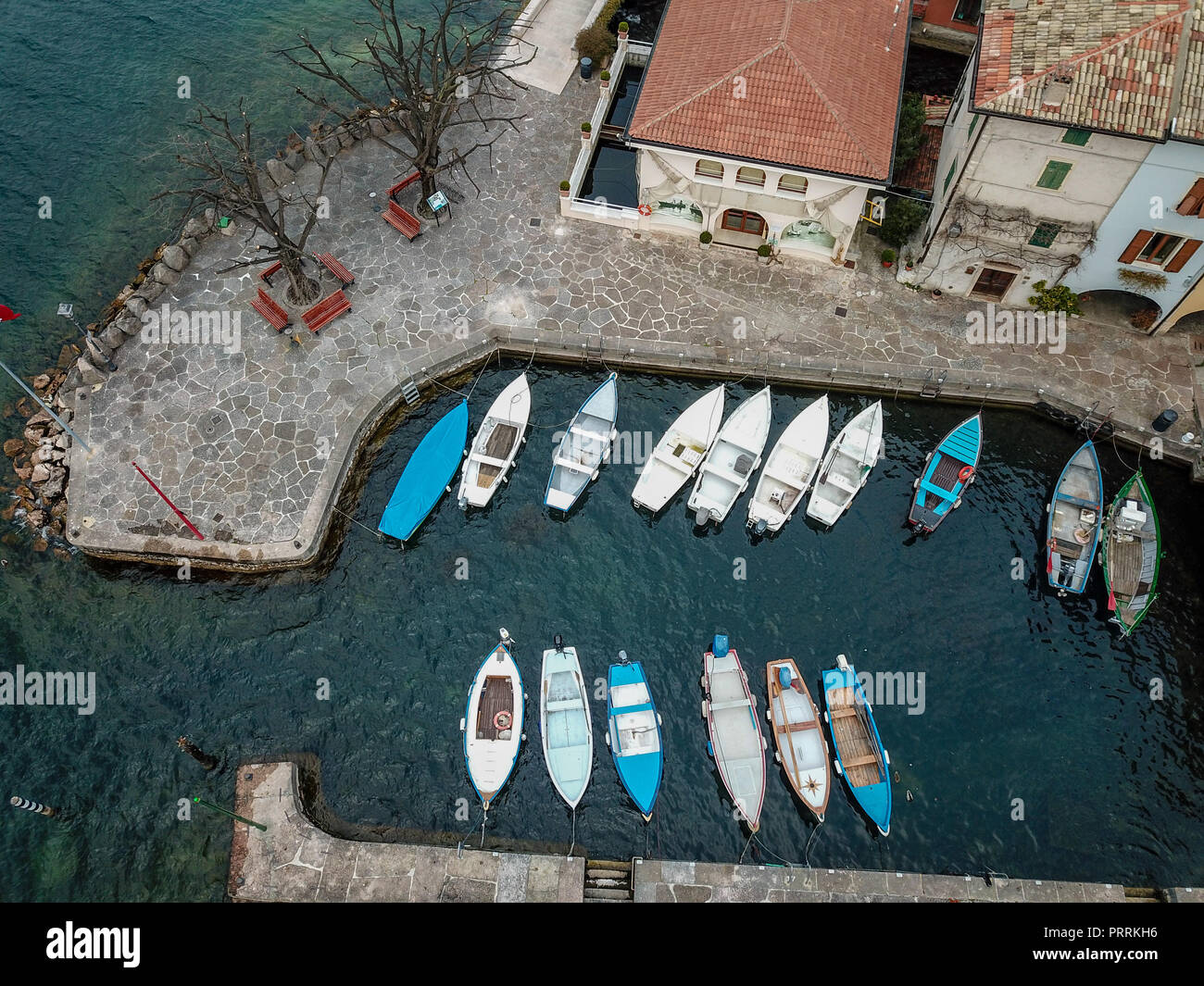 Bunte Segelboote angedockt am Gardasee neben Stadt, geschossen von Drohne Stockfoto