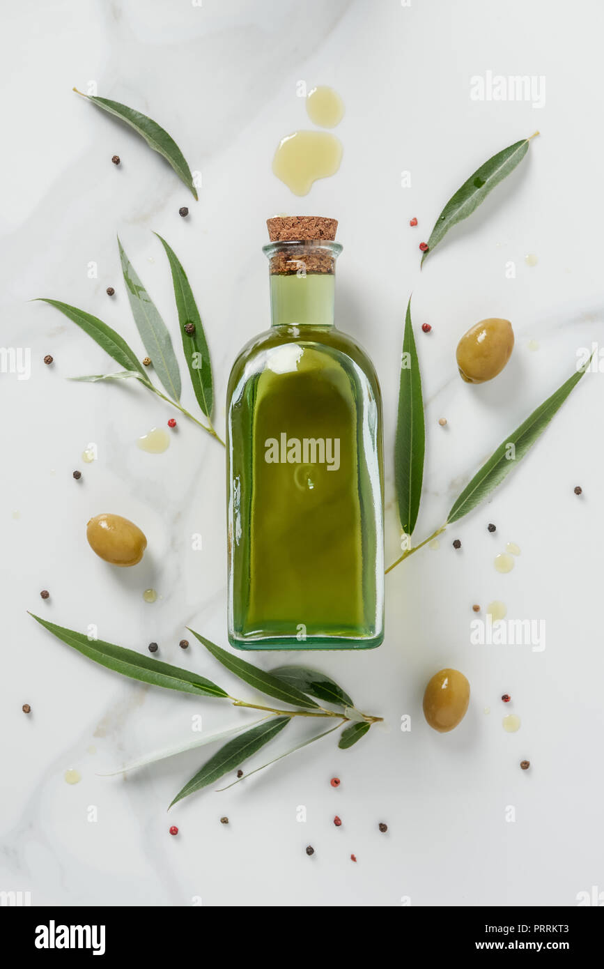 Foodstyling von Olivenöl Flasche und Oliven auf Marmor tisch Stockfoto