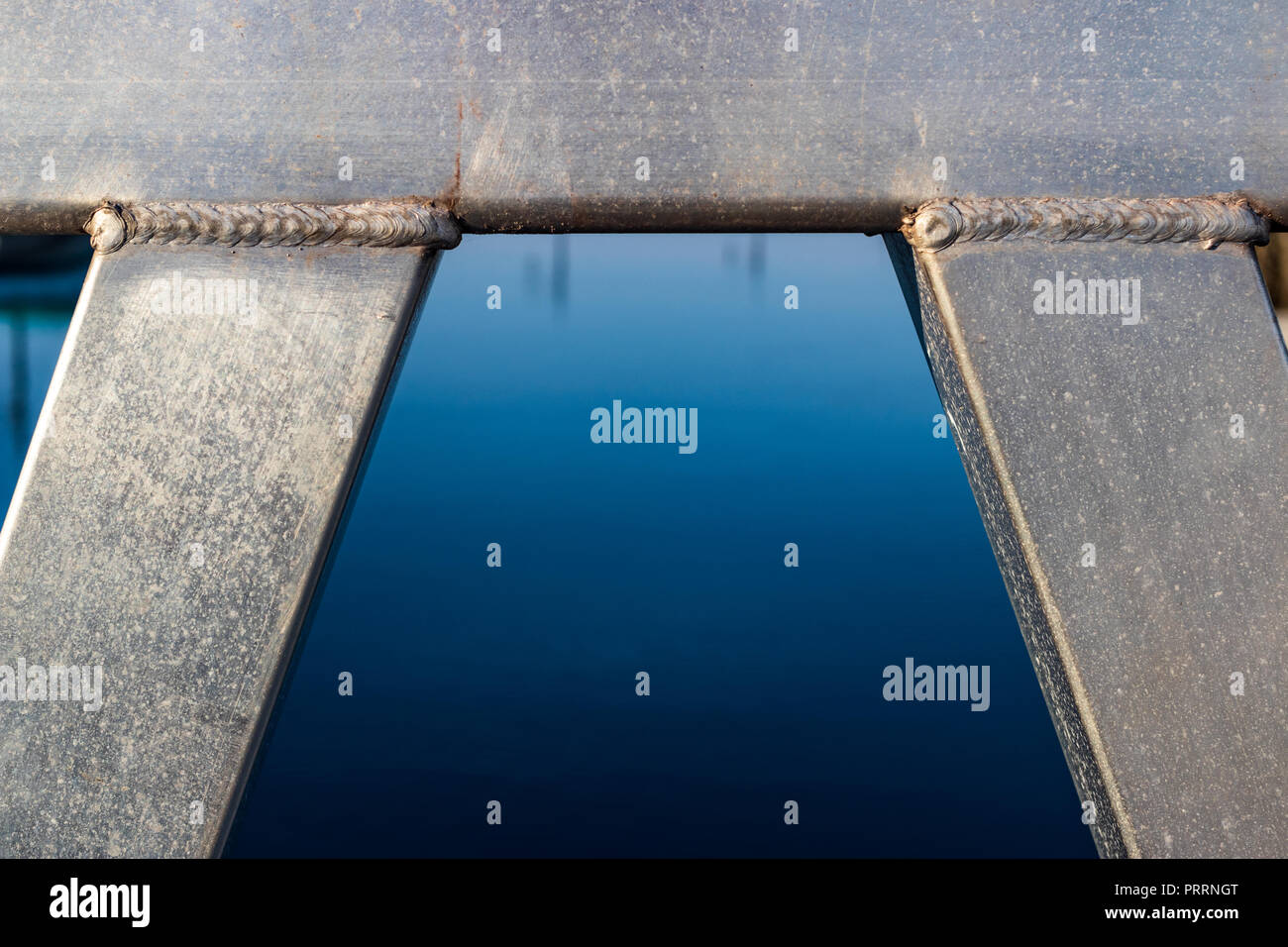 Geschweißte Rohre aus Aluminium Strahl in einem Bogen mit Wasser in die Mitte gerahmt Stockfoto