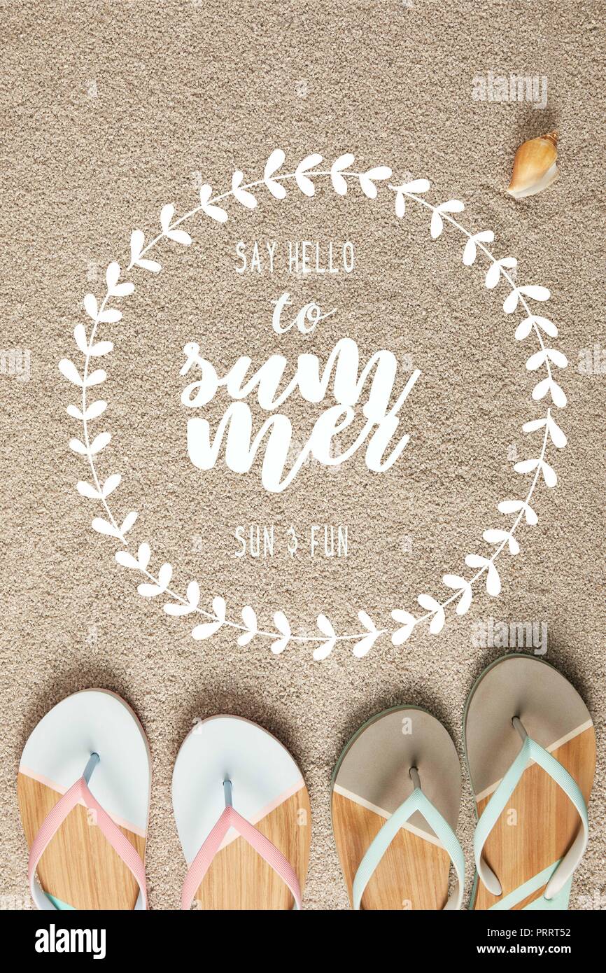 Flach mit Sommer Flip Flops und Muschel auf Sand mit 'Say hello zu Sommer' Schriftzug in floralen Frame Stockfoto