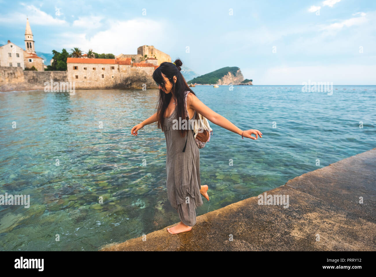 Frau Wandern auf Pier Seite mit Stari Grad (Altstadt) auf den Hintergrund in Budva, Montenegro Stockfoto