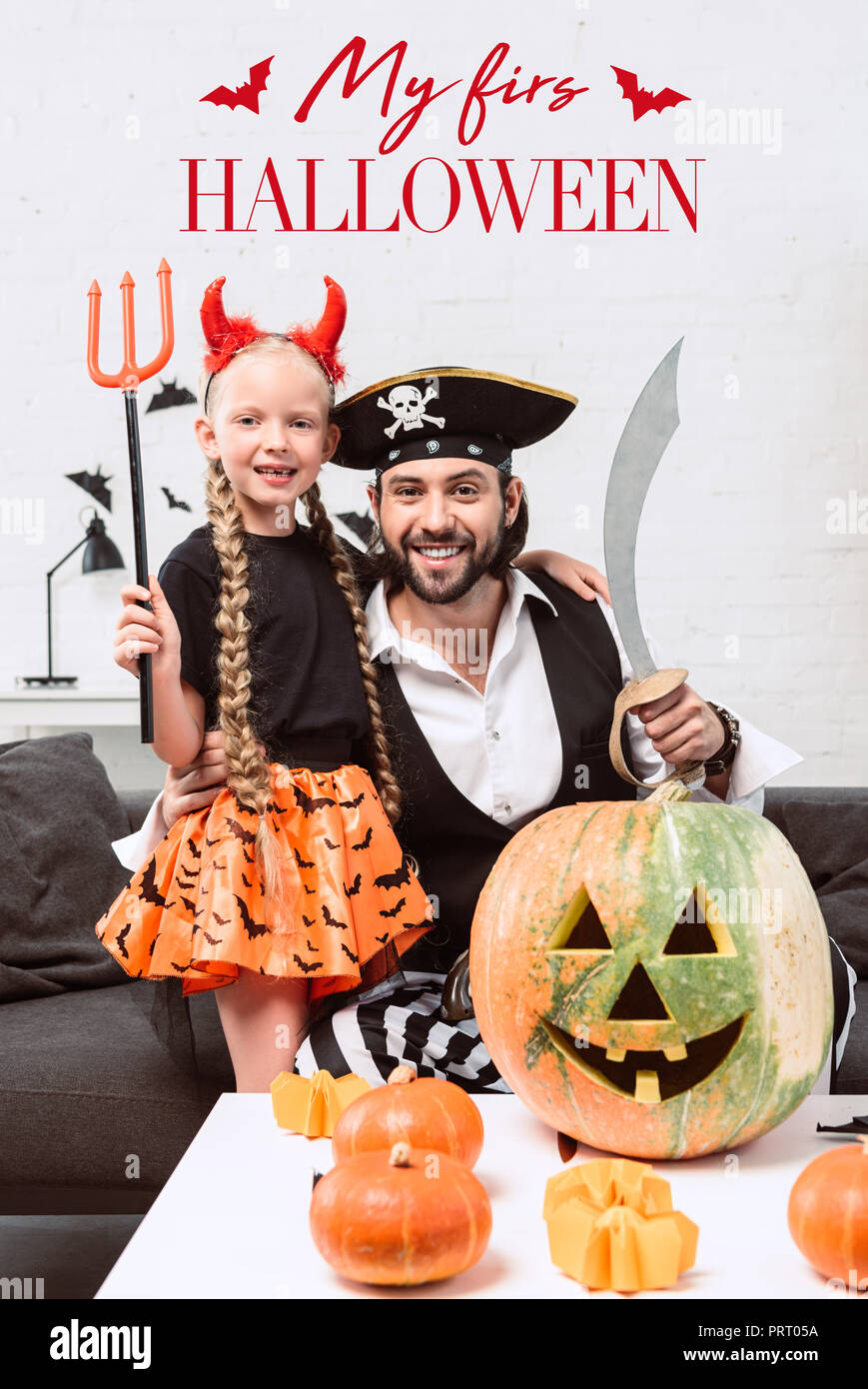 Glückliche Tochter und Vater in Halloween Kostüme zu Hause mit y bin zuerst Halloween' Schriftzug Stockfoto