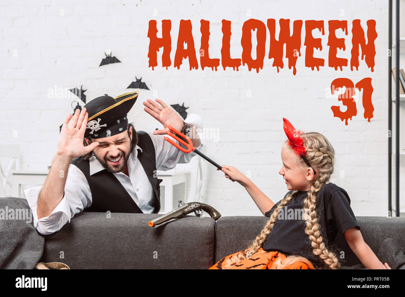 Portrait von Tochter und Vater in Halloween Kostüme zu Hause spielt mit 'Halloween 31'-Schriftzug Stockfoto