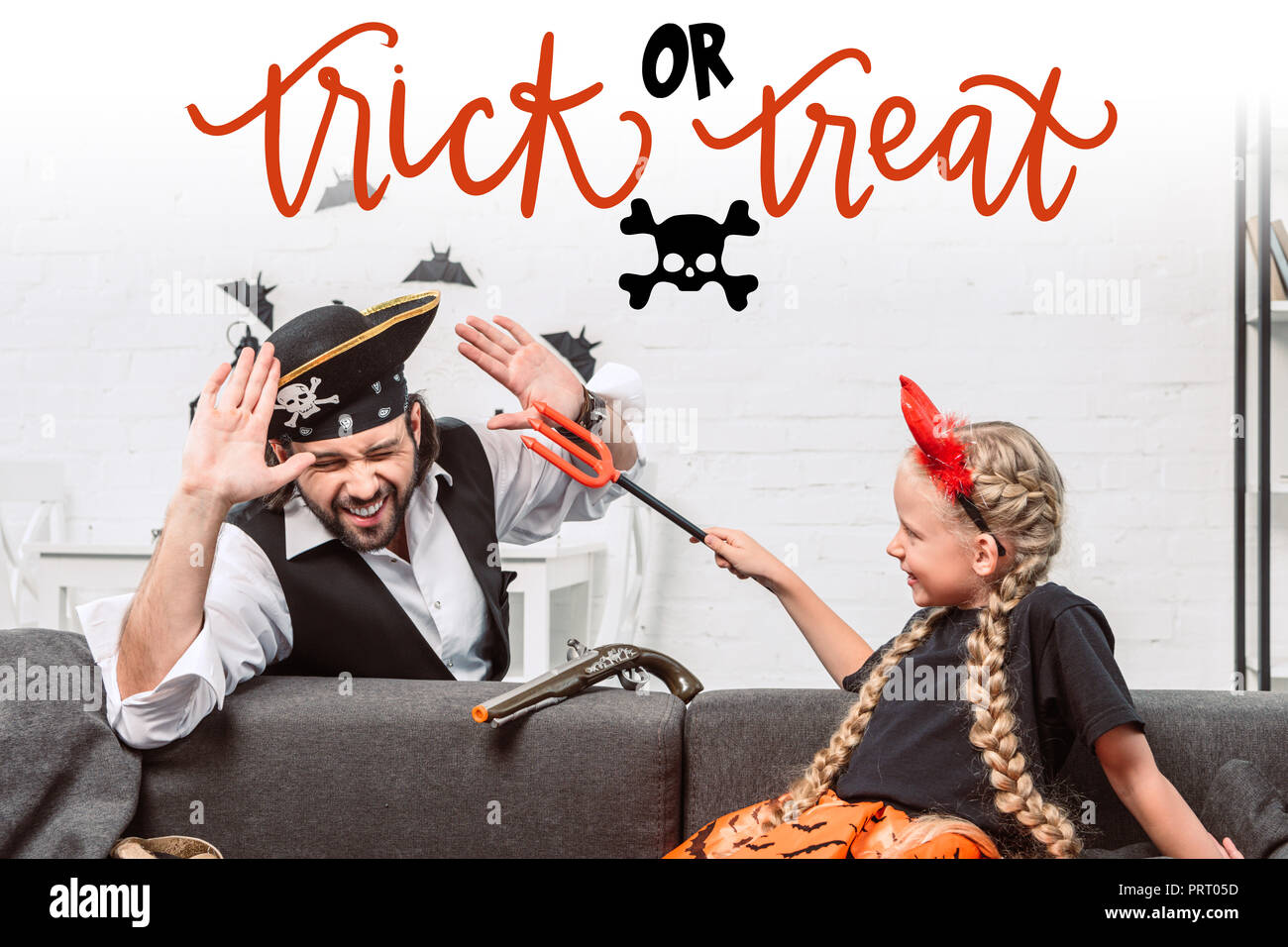 Portrait von Tochter und Vater in Halloween Kostüme zu Hause spielt mit "Trick or Treat"-Schriftzug Stockfoto