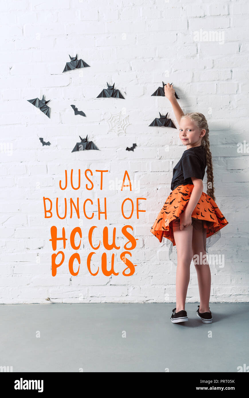 Rückansicht des Kindes in Rock hängenden schwarzen Papier Fledermäuse auf weißer Wand, halloween Urlaub Konzept mit "nur ein Haufen von Hocus Pocus' Schriftzug Stockfoto