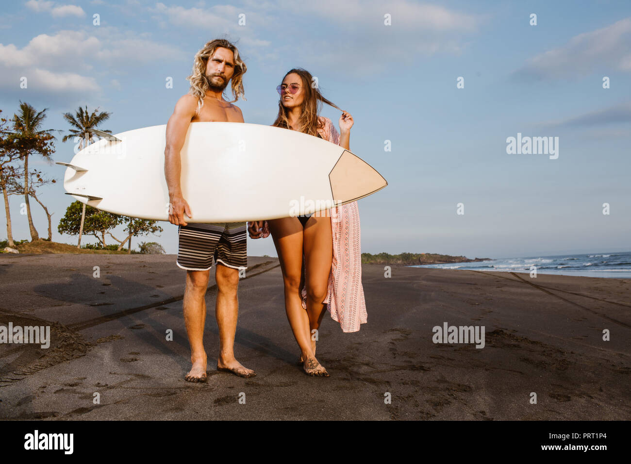 Paar stehend mit Surfbrett am Strand in Bali, Indonesien Stockfoto