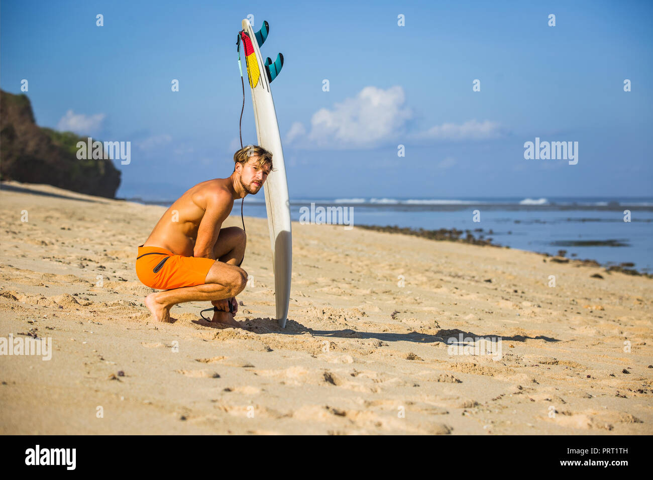Junger Mann mit Surfen am Sandstrand in der Nähe von Ocean Stockfoto