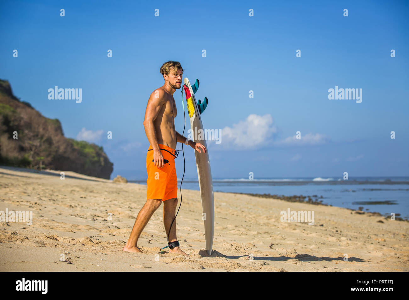 Seitenansicht des jungen Mannes mit Surfen am Sandstrand in der Nähe von Ocean Stockfoto