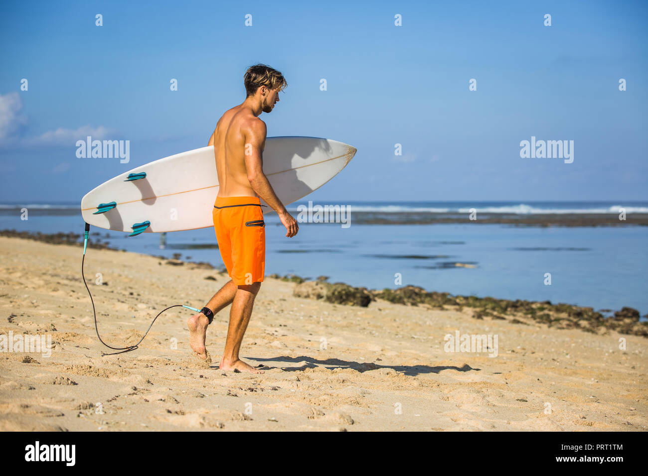 Jungen athletischen Sportler mit Surfen Board zu Fuß am Sandstrand Stockfoto