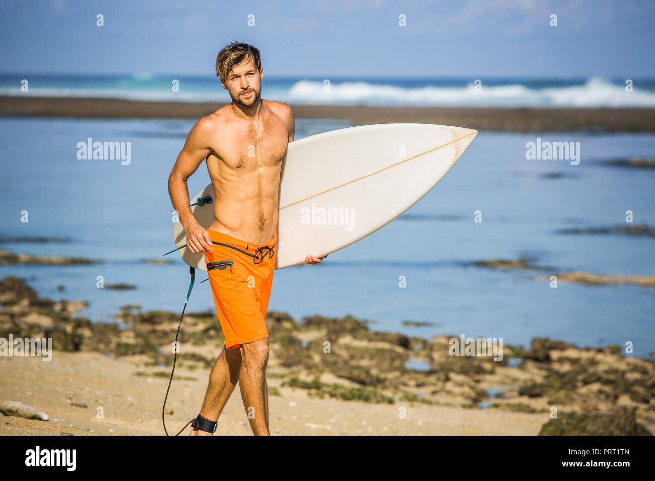 Surfer mit Surfen Board läuft auf Sandstrand auf Sommer Tag Stockfoto
